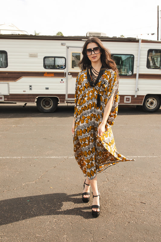Full length retro patterned caftan. Vintage inspired with golden leaf-like pattern and black and white accent design. V-Neck style with batwing sleeves and ankle hem. 