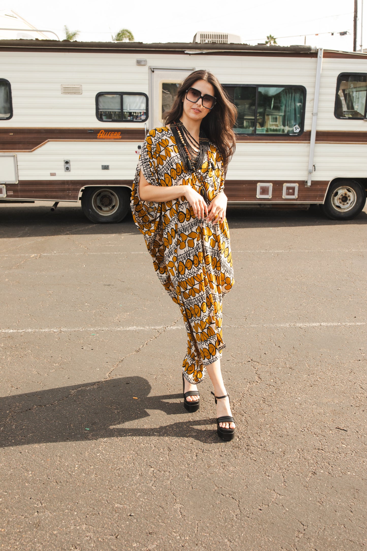 Full length retro patterned caftan. Vintage inspired with golden leaf-like pattern and black and white accent design. V-Neck style with batwing sleeves and ankle hem. 