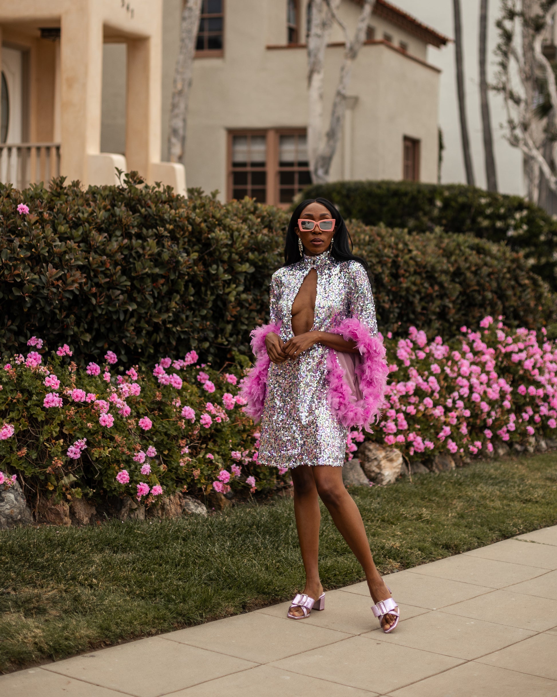 Glittery pastel sequins mock neck midi dress. Featuring long bell sleeves cuffed with rich pink feathers. The back features multiple closures to expose your back or hide bra straps as needed. May also be reversed and worn as a plunging deep-v neckline. Dress hem is just above knee.