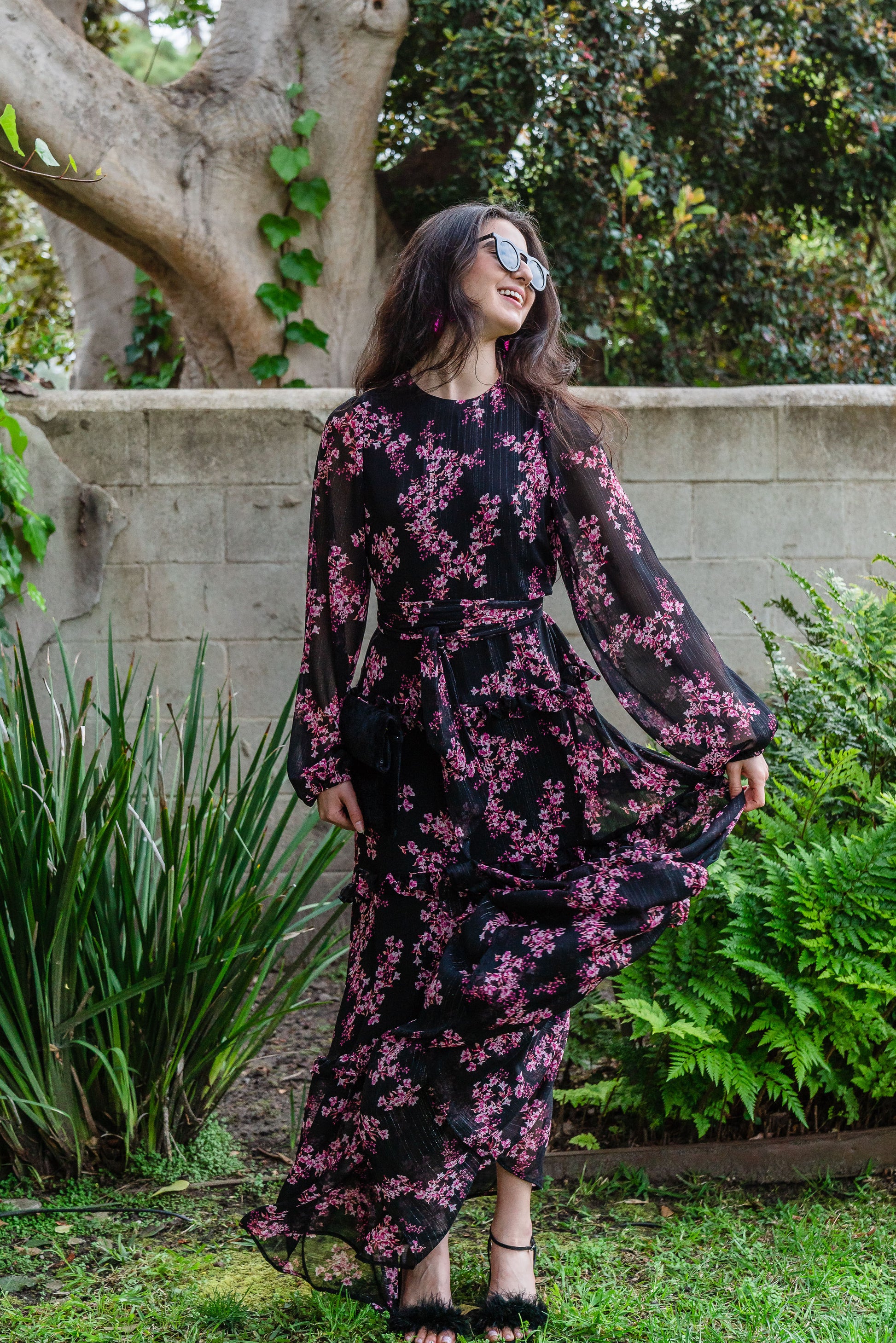 This floral maxi is crafted with a soft, metallic infused fabric, it features high neck, bishop sleeves, tiered ruffle skirt and matching sash for a cinched waist.