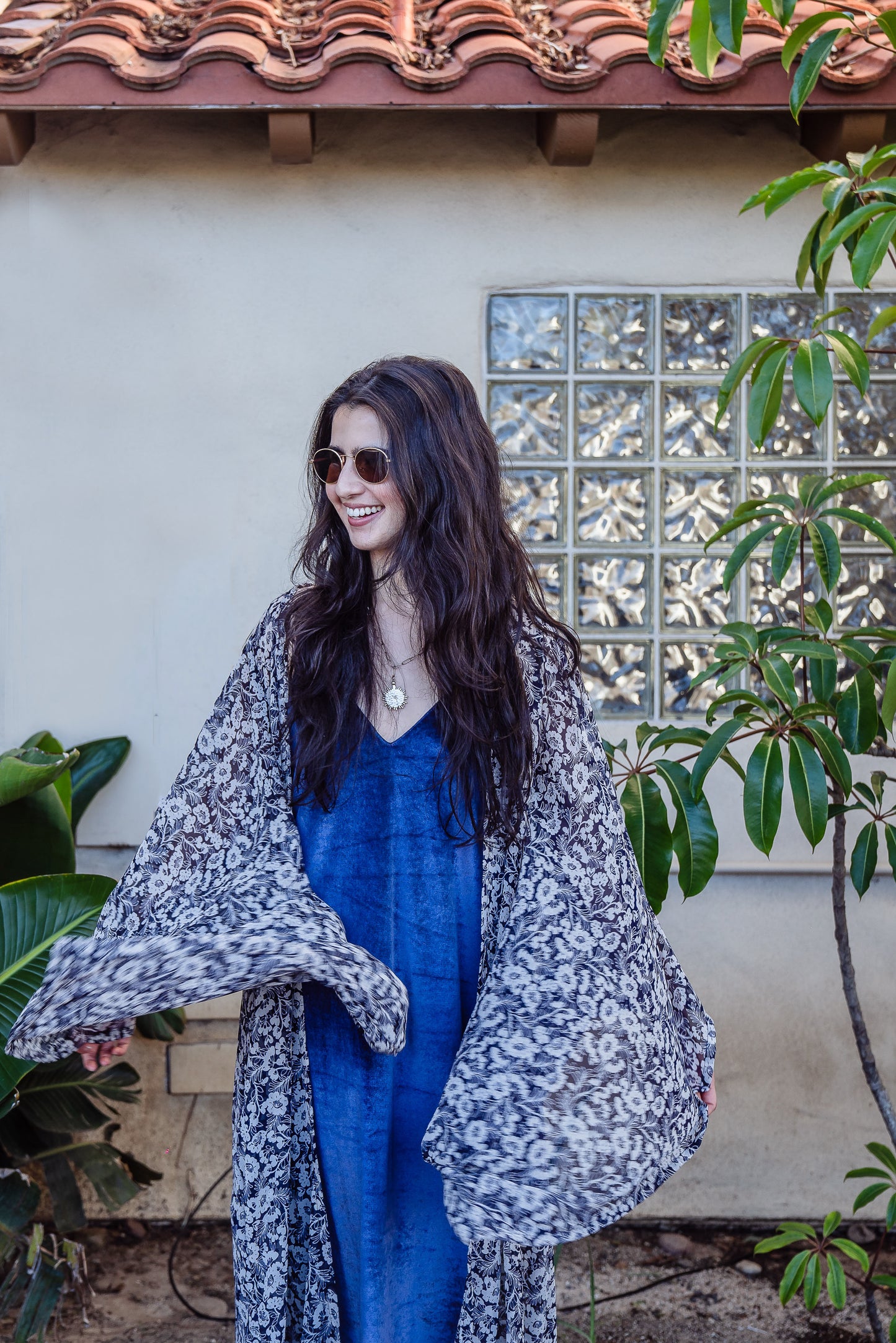 A white and dark blue floral patterned kimono robe featuring long, wide, rectangular sleeves, a full-length cut, deep pockets, and a matching tie belt for an optional cinched waist.