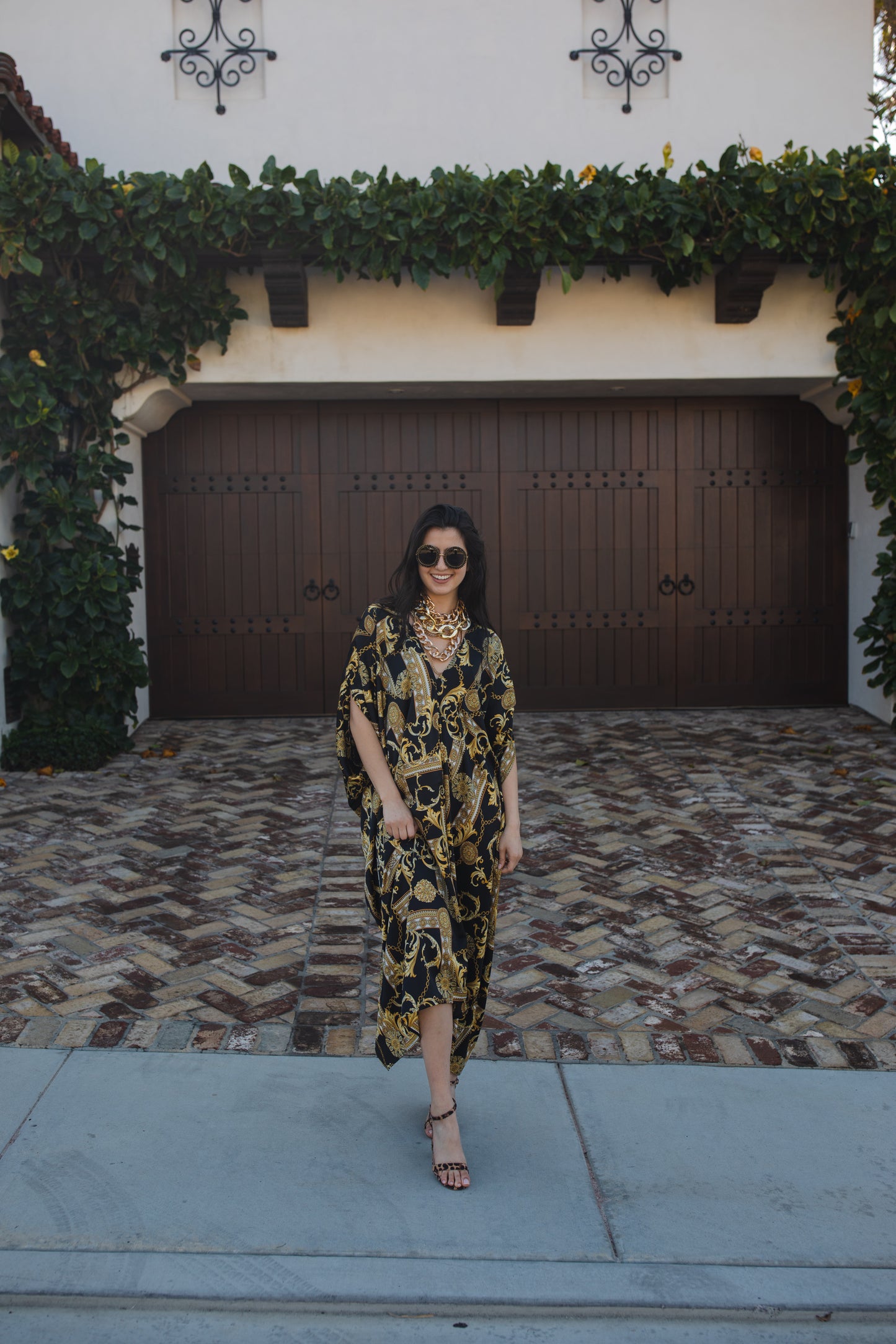 Opaque black caftan dress featuring yellow gold ornamental filigree patterned design. Featuring a deep v-neckline, short batwing sleeves, and an ankle-length hem. This caftan is a voluminous garment that gives a flowy silhouette that drapes beautifully on all shapes.