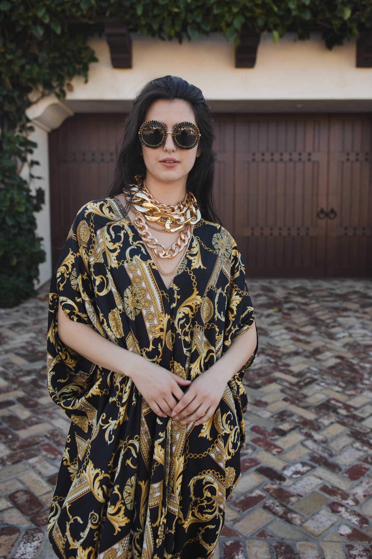 Opaque black caftan dress featuring yellow gold ornamental filigree patterned design. Featuring a deep v-neckline, short batwing sleeves, and an ankle-length hem. This caftan is a voluminous garment that gives a flowy silhouette that drapes beautifully on all shapes.