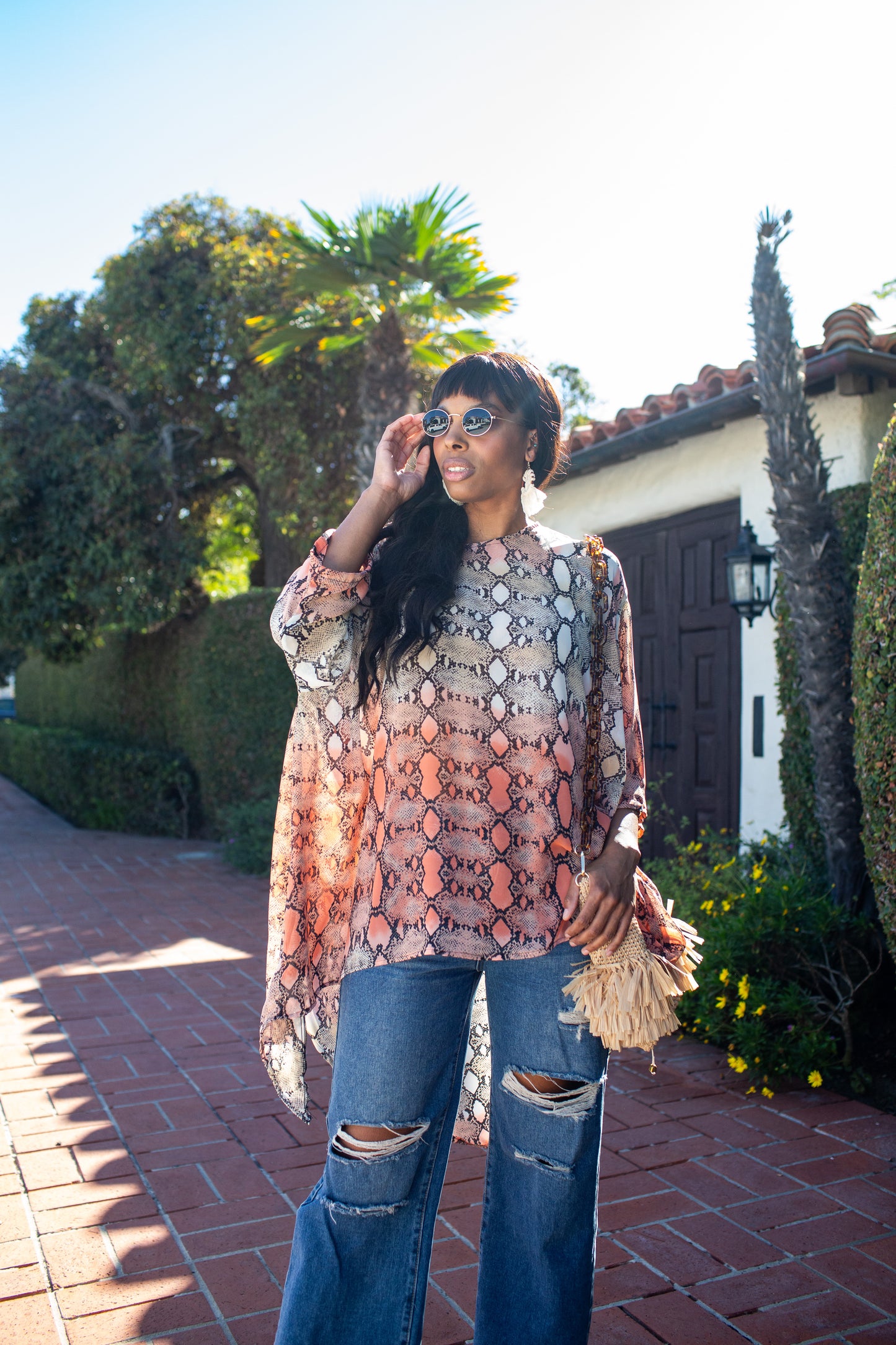 This orange and turquoise snakeskin print top features a wide boat neckline, gracefully exposing the collarbone, while batwing sleeves extend from the shoulders, flowing freely like a soft cascade of fabric. The waist-length hem adds a touch of structure, making it versatile for styling. 