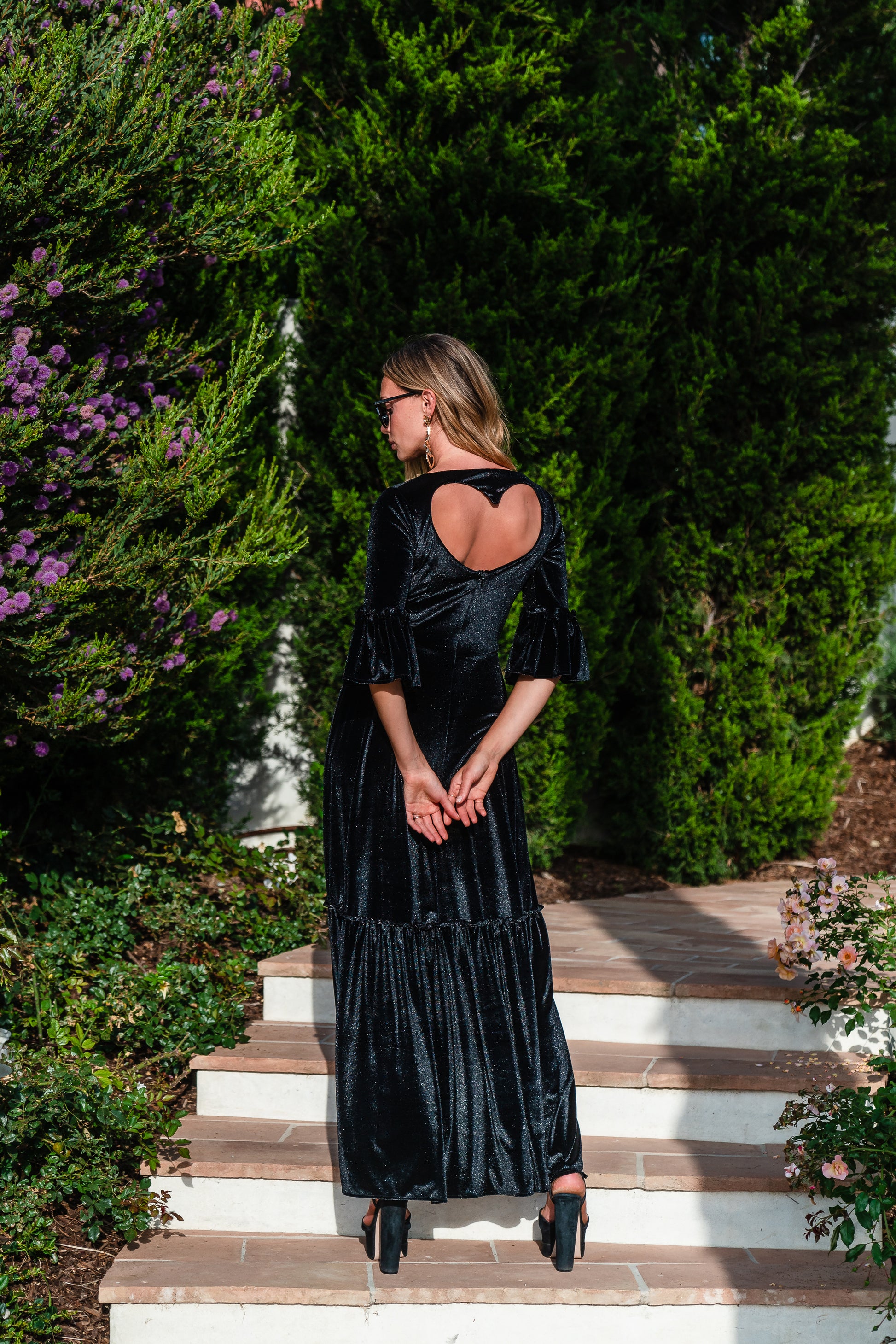 Shimmery black maxi dress with ruffle skirt and ruffled half sleeves. Featuring v-neck frontn and heart-shaped cutout in back, this dark dress is a gothic dream.