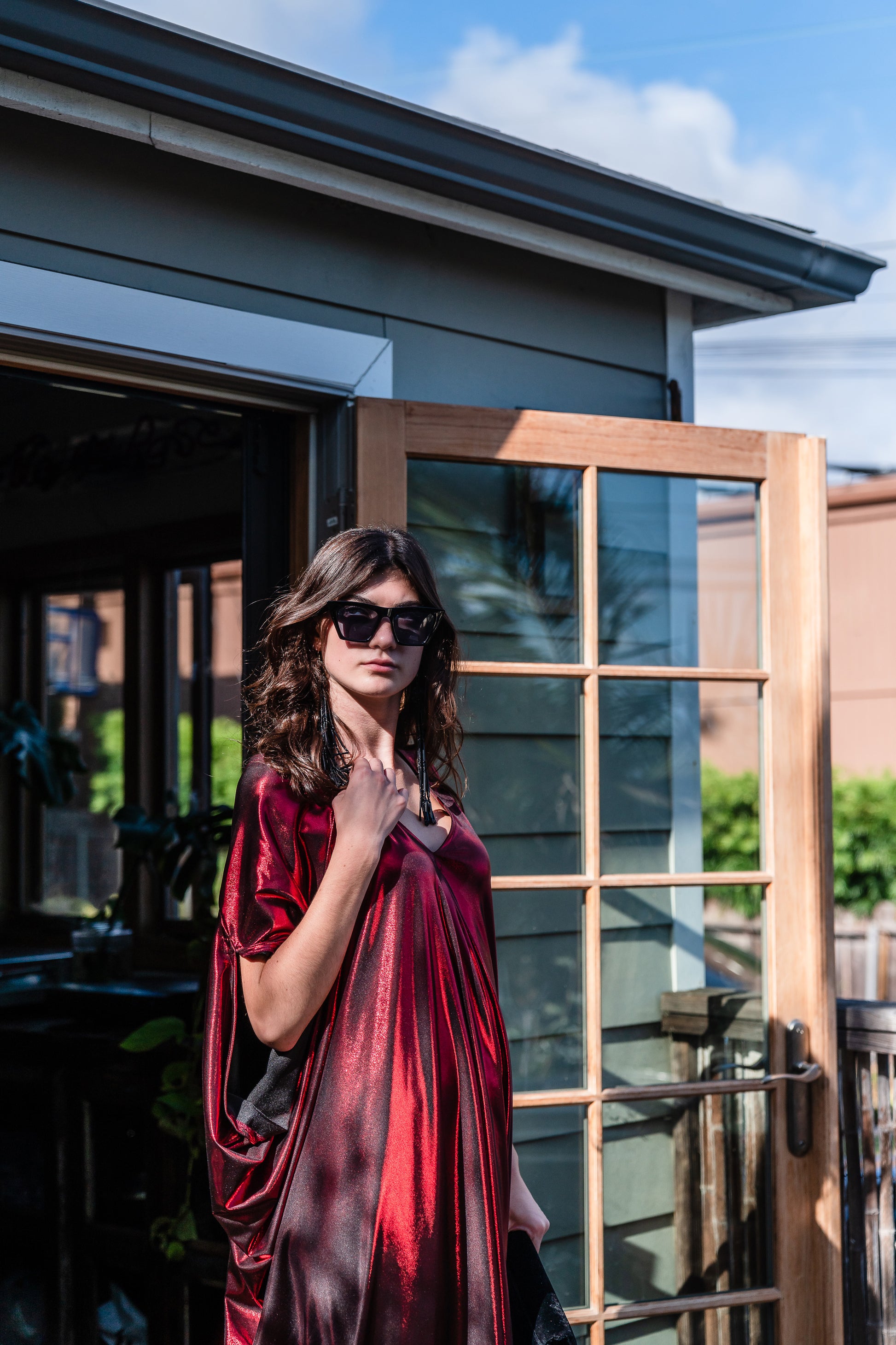 A metallic solid red caftan featuring batwing sleeves, a deep v neckline, and ankle length hem. 