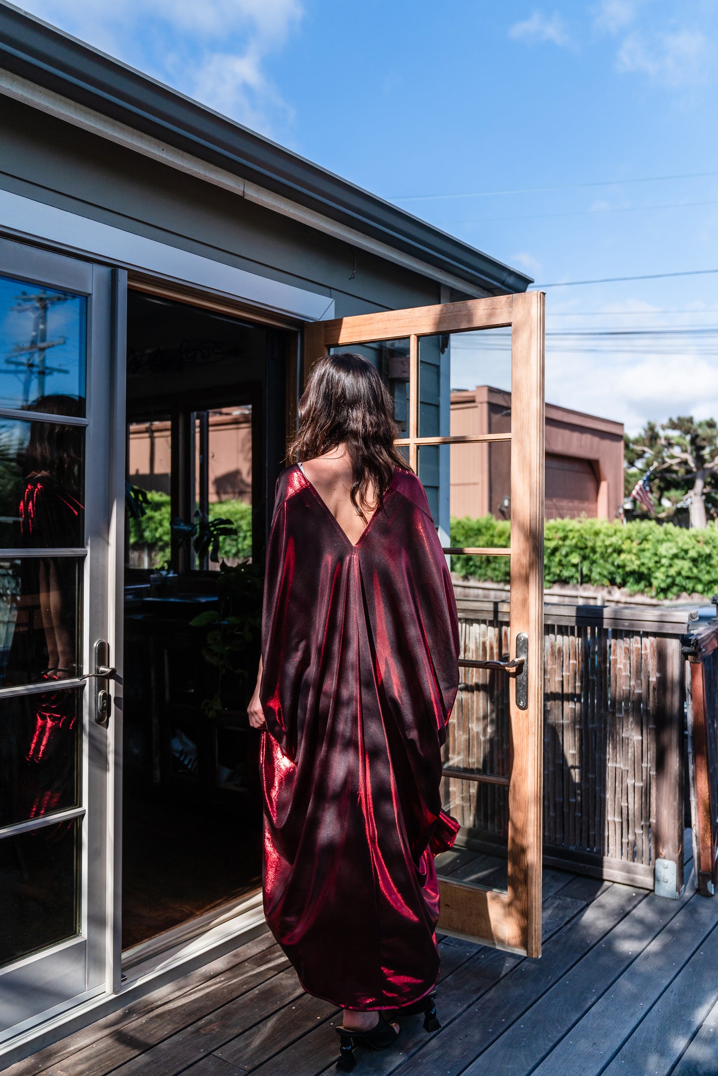 A metallic solid red caftan featuring batwing sleeves, a deep v neckline, and ankle length hem. 