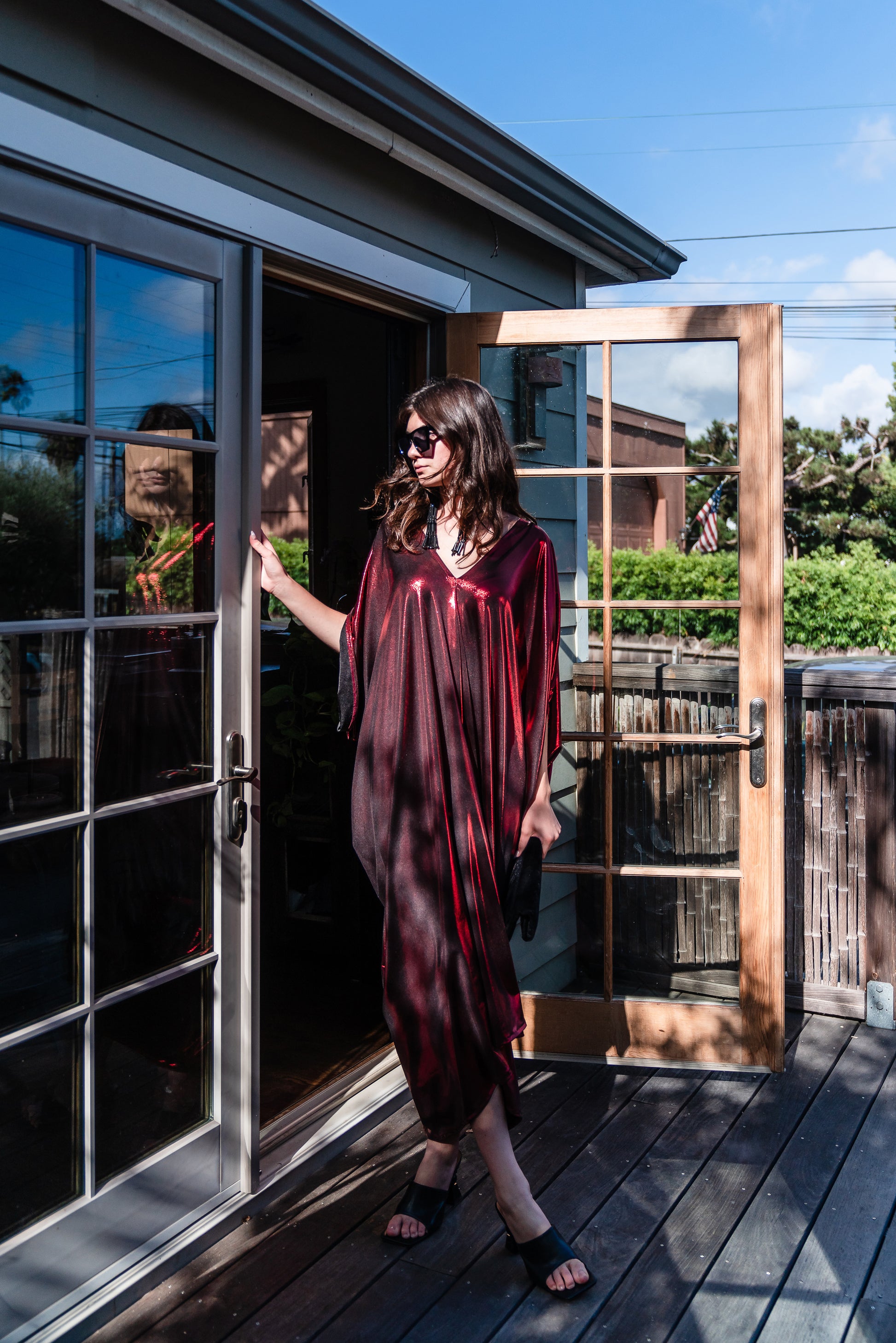 A metallic solid red caftan featuring batwing sleeves, a deep v neckline, and ankle length hem. 