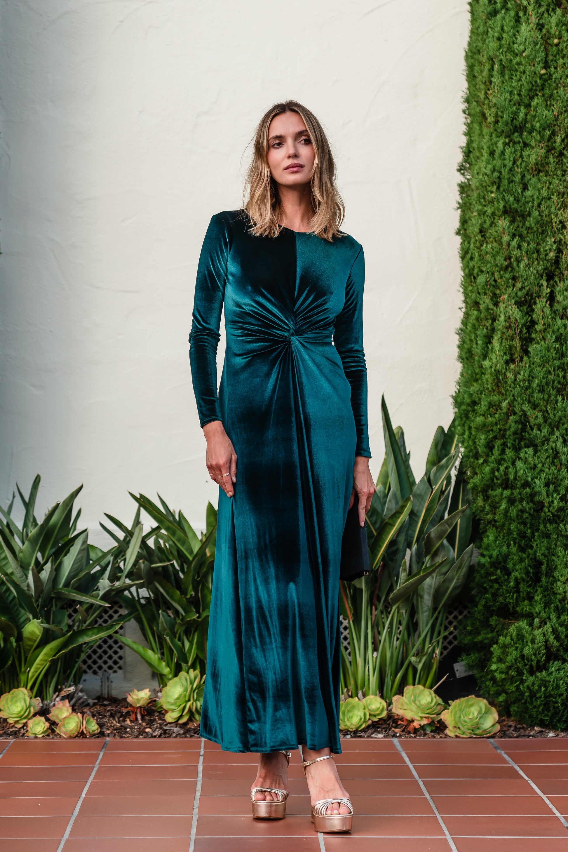 A stunning floor-length emerald velvet dress with long sleeves, elastic and a flattering knot detail at the waist.