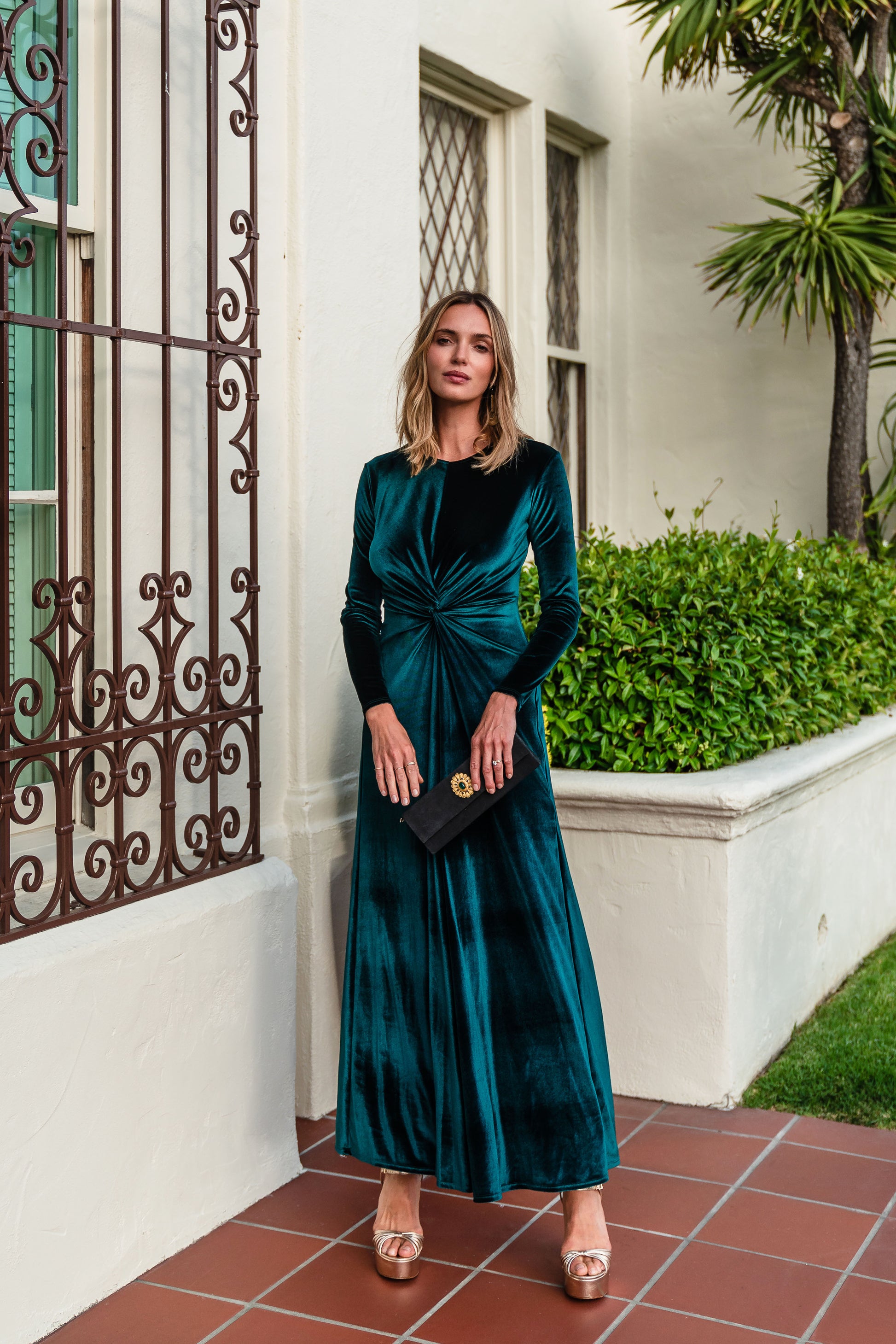 A stunning floor-length emerald velvet dress with long sleeves, elastic and a flattering knot detail at the waist.