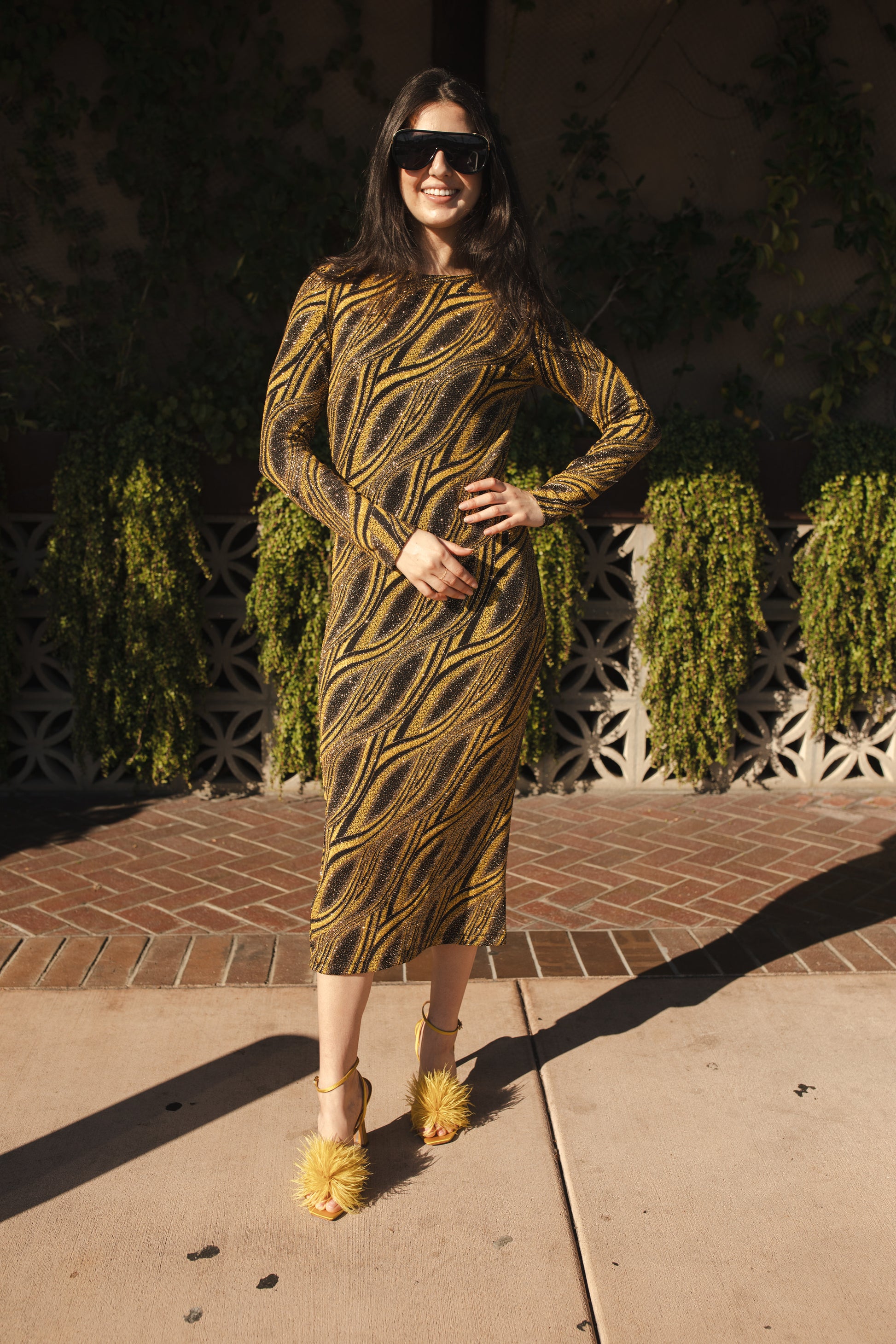 This pop-art bodycon dress accentuates your curves, while the removable feather trim on the sleeves adds a touch of elegance. The yellow cuffs and black and yellow fabric are perfect for those who shine bright.