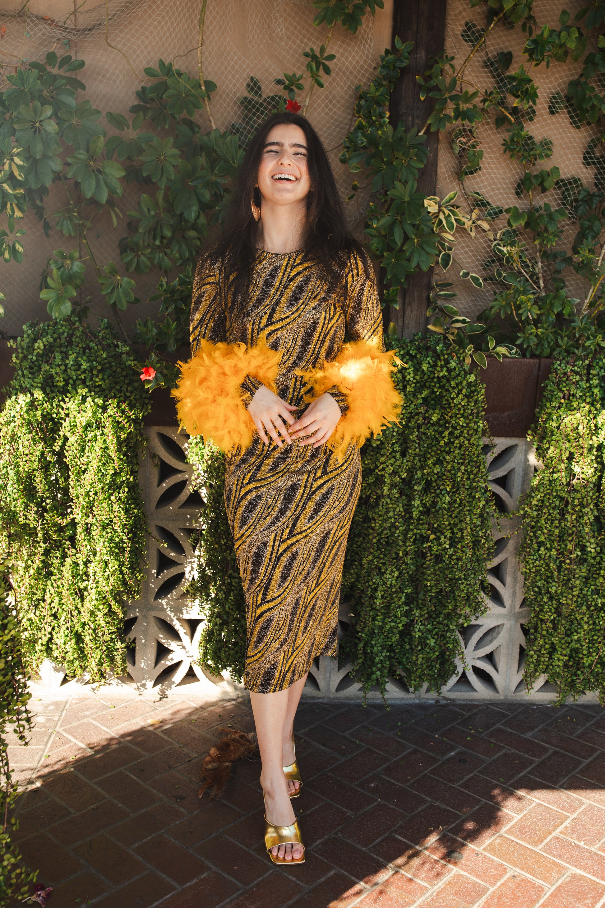 This pop-art bodycon dress accentuates your curves, while the removable feather trim on the sleeves adds a touch of elegance. The yellow cuffs and black and yellow fabric are perfect for those who shine bright.