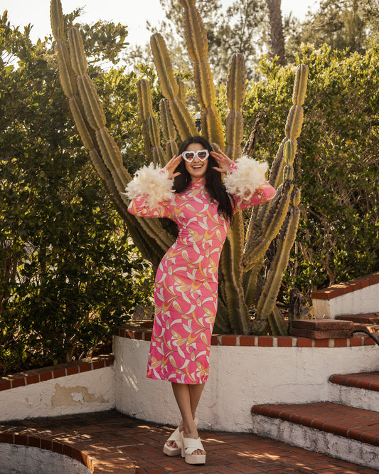 This pop-art bodycon design accentuates your curves, while the removable feather trim on the sleeves adds a touch of elegance.