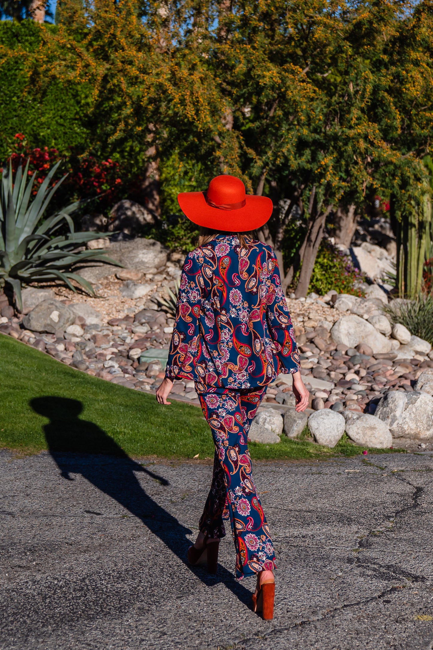 The Pepper Paisley Tuxedo Jacket. This retro glam suit jacket features a teal and rust paisley print. Has a wrist length arm hem, loose collar, and no button. 