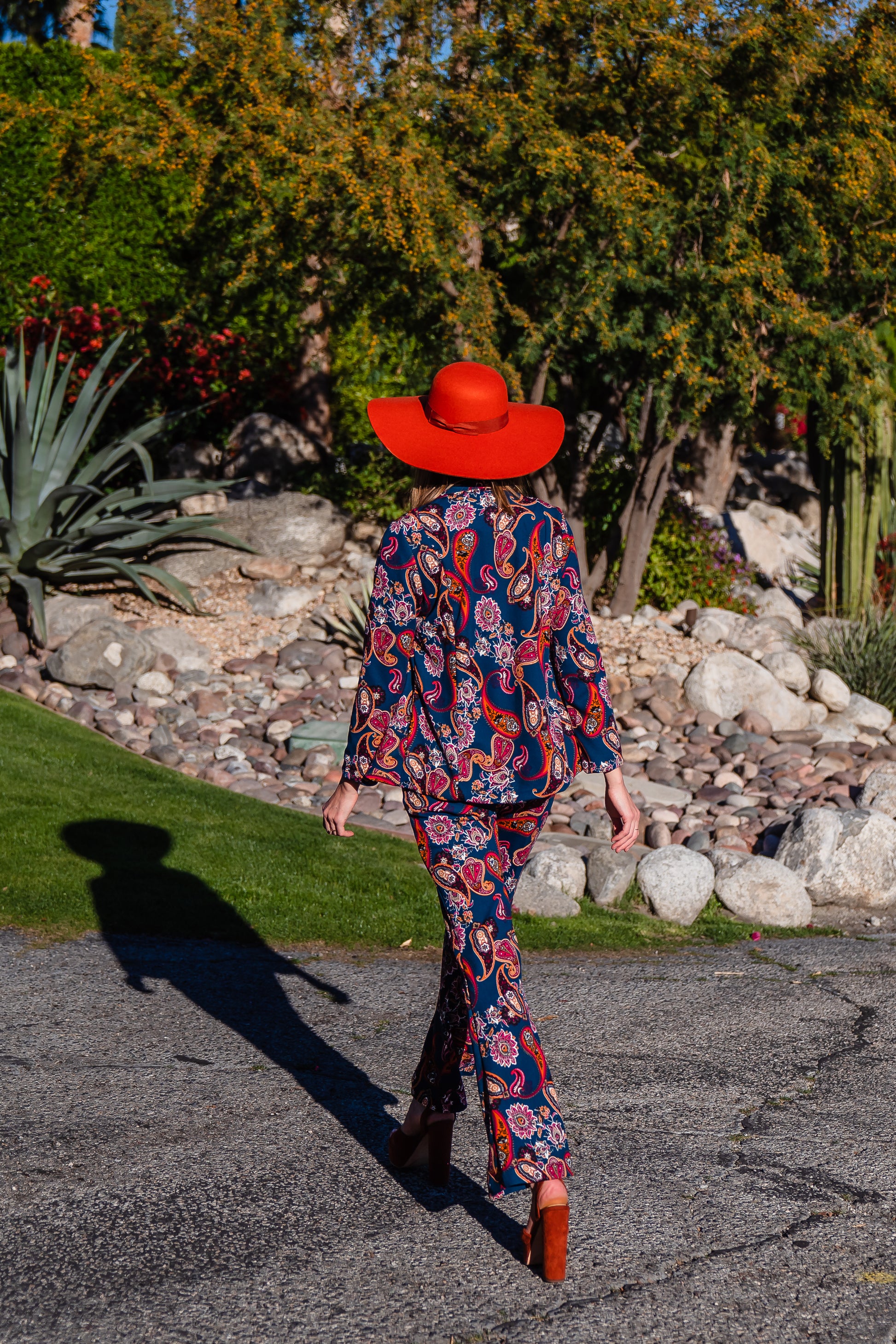 The Pepper Paisley Tuxedo Jacket. This retro glam suit jacket features a teal and rust paisley print. Has a wrist length arm hem, loose collar, and no button. 