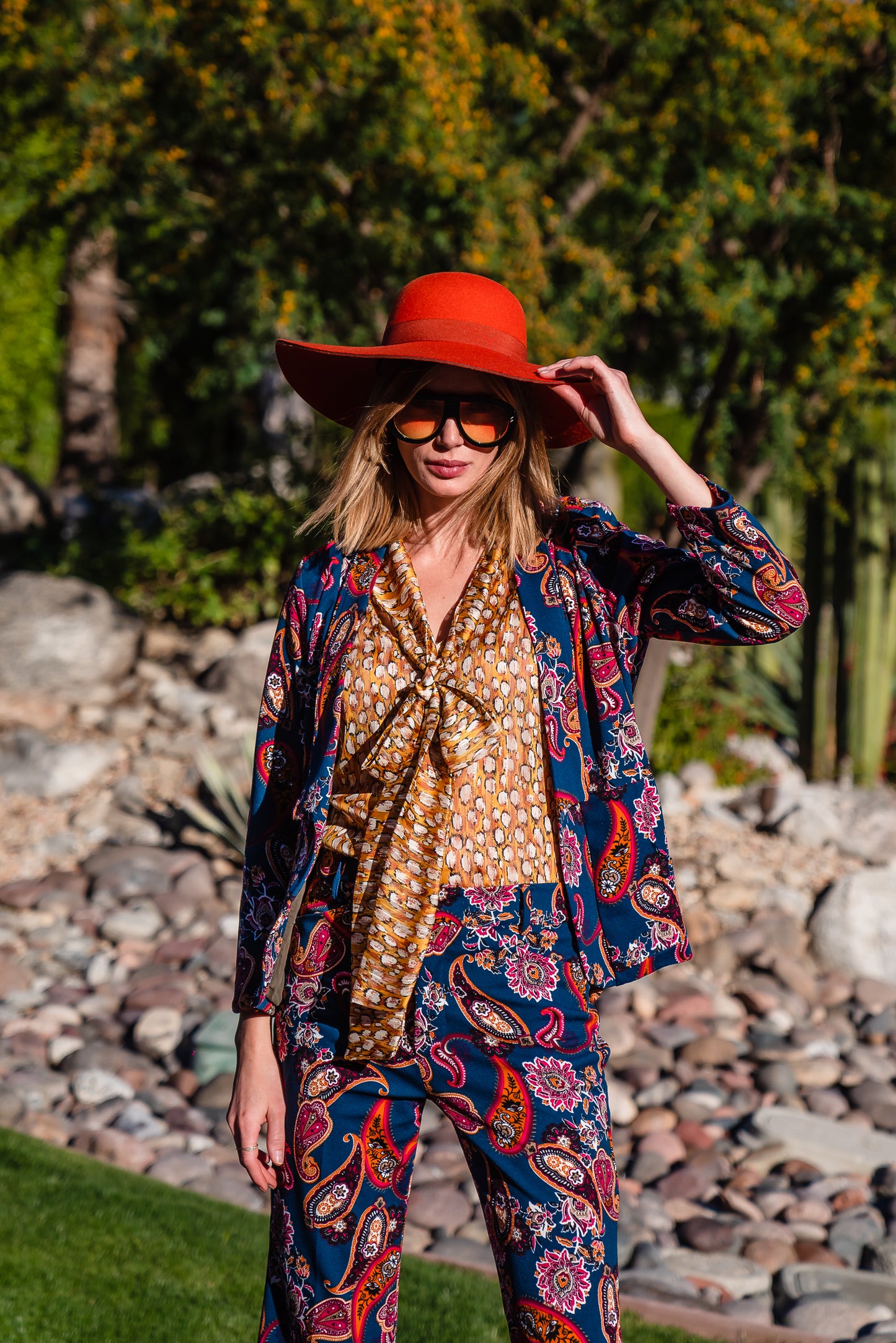 The Pepper Paisley Tuxedo Jacket. This retro glam suit jacket features a teal and rust paisley print. Has a wrist length arm hem, loose collar, and no button. 