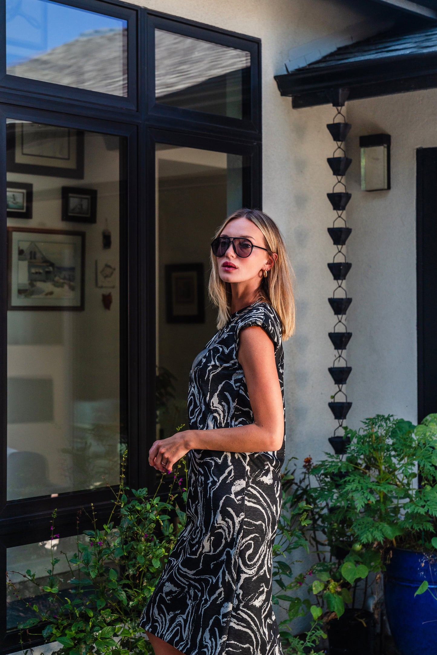 Knee length sleeveless shift dress, in a black and taupe abstract, marble like pattern, the dress has shoulder pads.