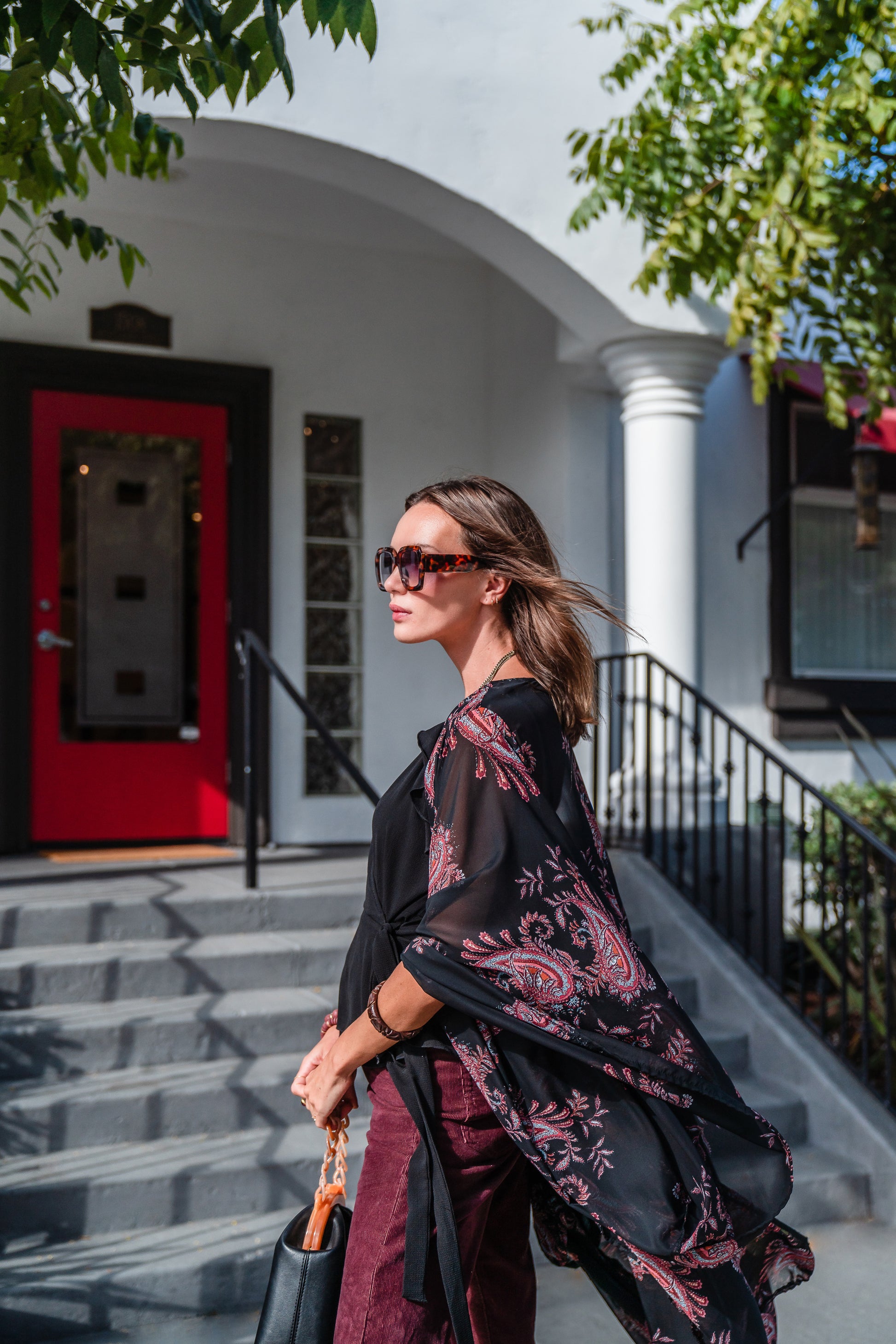 Introducing our Vera Paisley Kimono, with a black chiffon material is accented with a dark paisley pattern and pops of bordeaux, tan, and turquoise. 